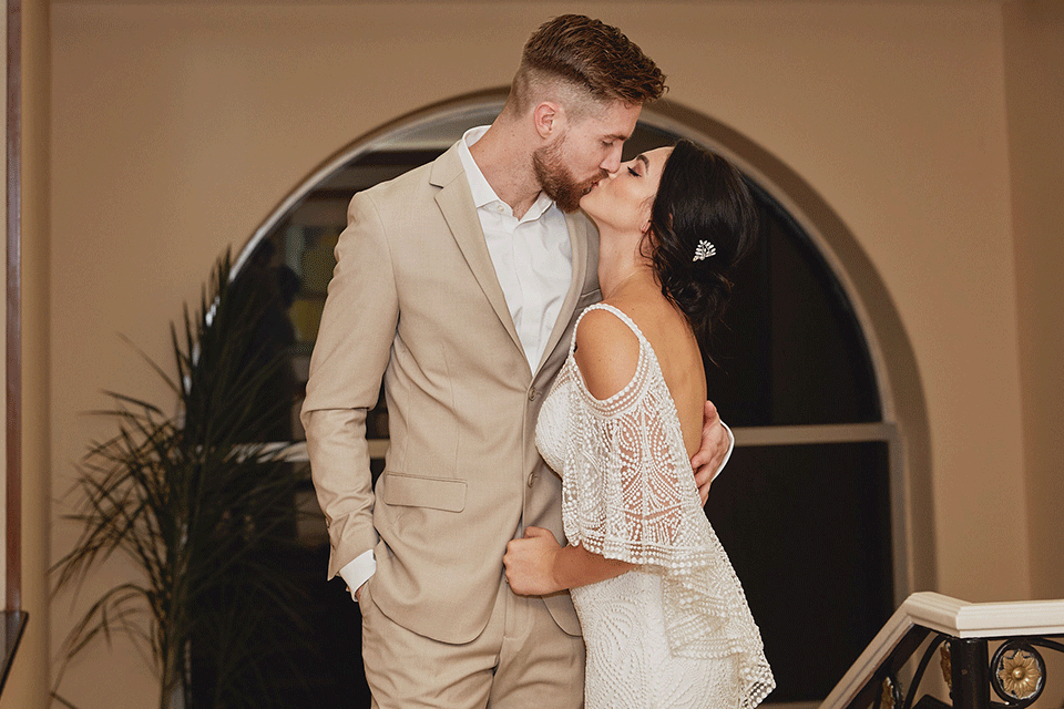 Grand-Firesta-Americana-Coral-Beach-bride-and-groom-kiss-groom-in-tan-groom-in-tan-suit-bride-in-bohemian-gown