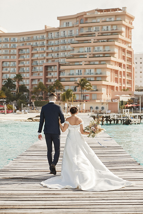 Grand-Firesta-Americana-Coral-Beach-bride-and-groom-walking-away-on-dock