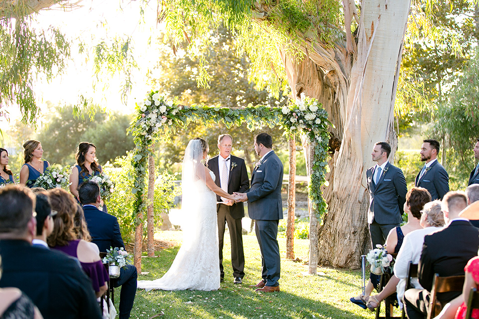 ggallaway-downs-wedding-bride-and-groom-at-ceremony-bride-in-a-lace-a-line-gown-and-groom-in-a-navy-blue-suit-with-a-white-long-tie