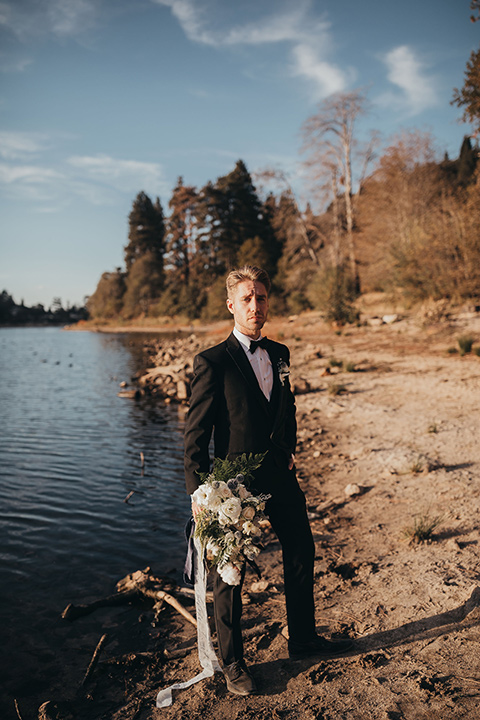 Big-Bear-Elopement-Shoot-groom-holding-flowers-in-a-tuxedo-and-black-bow-tie