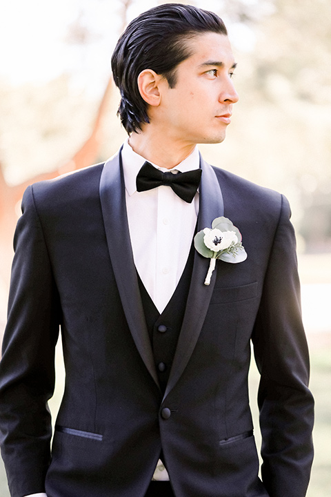 groom in a black shawl lapel tuxedo with a black bow tie