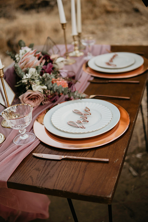 wooden tables with pink aisle runners with gold chargers and white plates