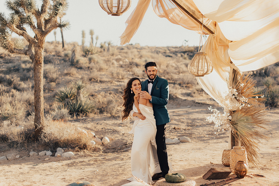 Bride and groom pose for a photo with the desert in the background