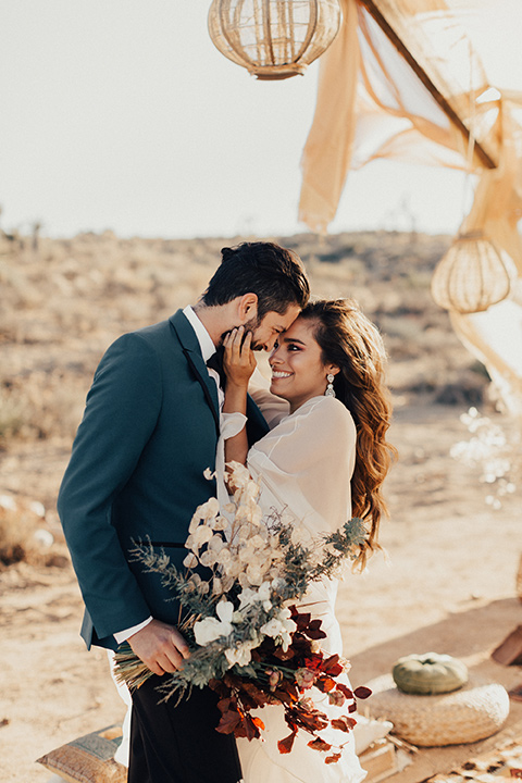 A bride and groom embrace each other for a wedding photo in the desert