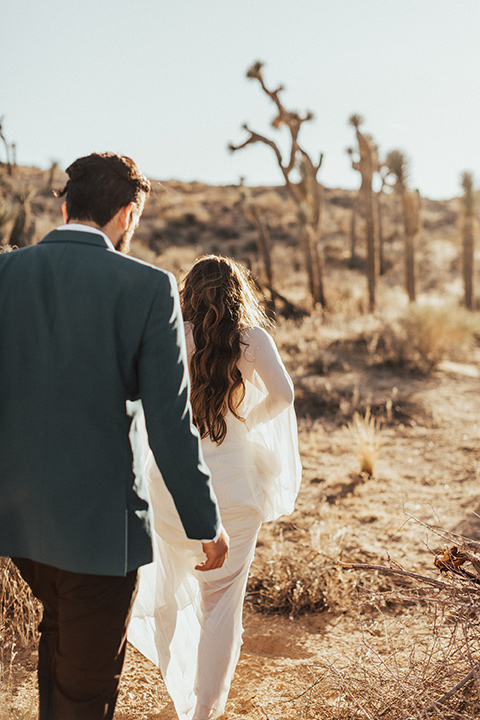 Photo from behind of the bride and groom walking in the desert