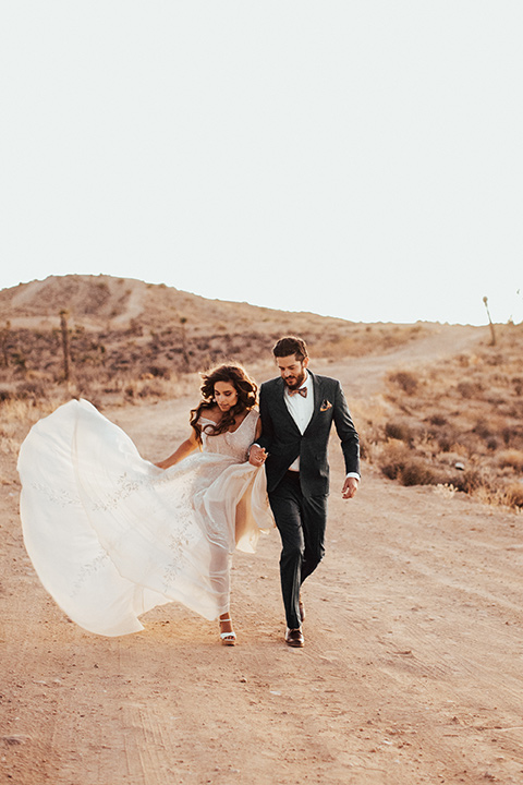 Bride and groom run in the desert 