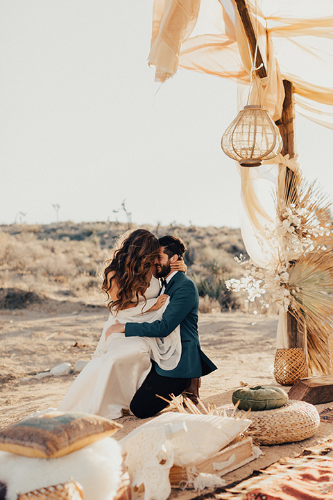 bride and groom embrace each other with the desert in the background