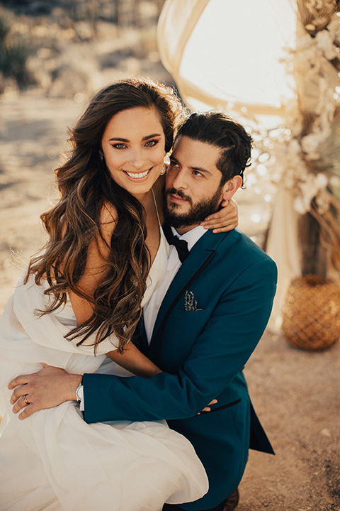 Bride sits with groom for a wedding photo in Joshua Tree