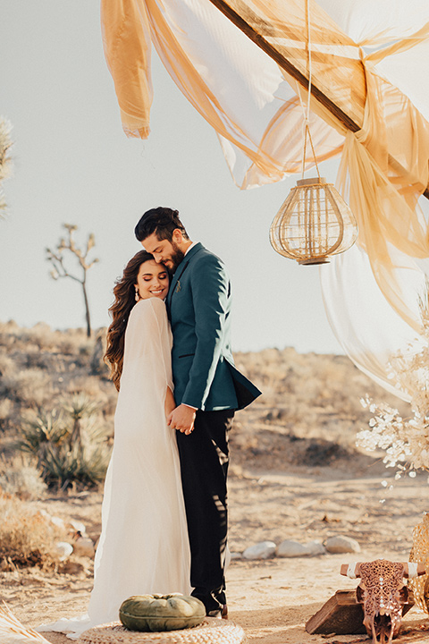 Groom looks down at the bride with a Joshua tree in the distance