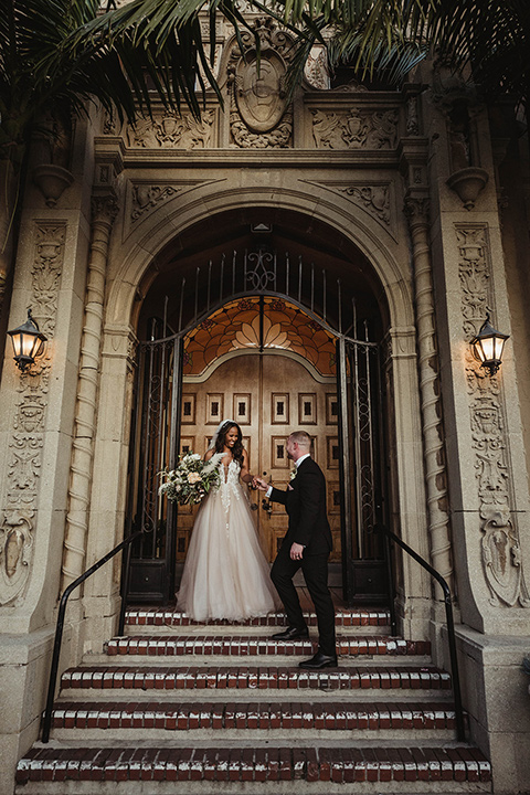 The-Ebell-In-Long-Beach-Wedding-bride-and-groom-by-steps-bride-in-a-champagne-ballgown-with-a-strapless-neckline-and-the-groom-in-a-black-tuxedo-with-a-rose-gold-bow-tie