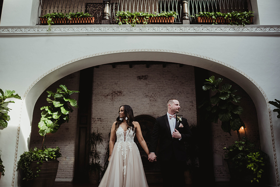 The-Ebell-In-Long-Beach-Wedding-bride-and-groom-looking-in-different-directions-bride-in-a-champagne-ballgown-with-a-strapless-neckline-and-the-groom-in-a-black-tuxedo-with-a-rose-gold-bow-tie