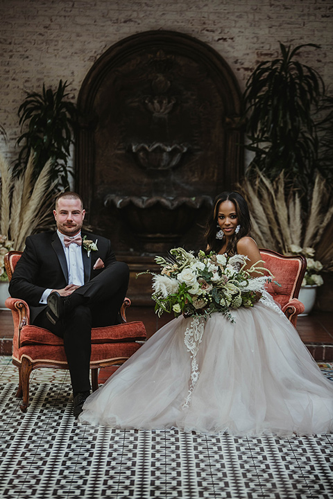 The-Ebell-In-Long-Beach-Wedding-bride-and-groom-sitting-bride-in-a-strapless-ballgown-and-groom-in-a-black-tuxedo-with-a-rose-gold-bow-tie