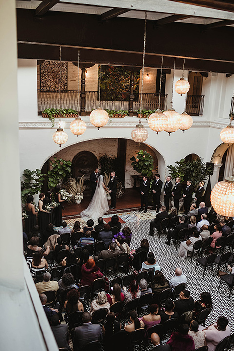 The-Ebell-In-Long-Beach-Wedding-ceremony-view-bride-in-a-strapless-ballgown-and-groom-in-a-black-tuxedo-with-a-rose-gold-bow-tie