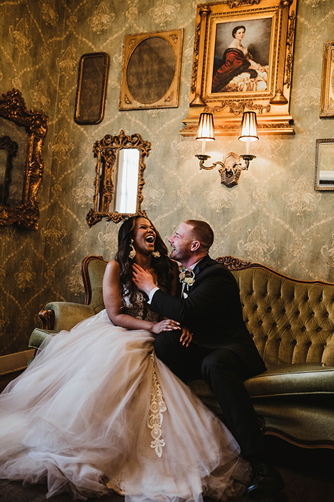 The-Ebell-In-Long-Beach-Wedding-couple-sitting-inside-bride-sitting-bride-in-a-strapless-ballgown-and-groom-in-a-black-tuxedo-with-a-rose-gold-bow-tie