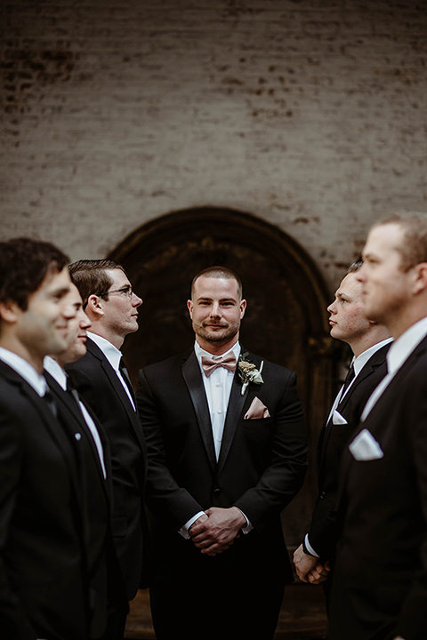 The-Ebell-In-Long-Beach-Wedding-group-groomsmen-photo-everyone-in-black-tuxedos-with-black-long-ties-and-groom-in-a-rose-gold-bow-tie