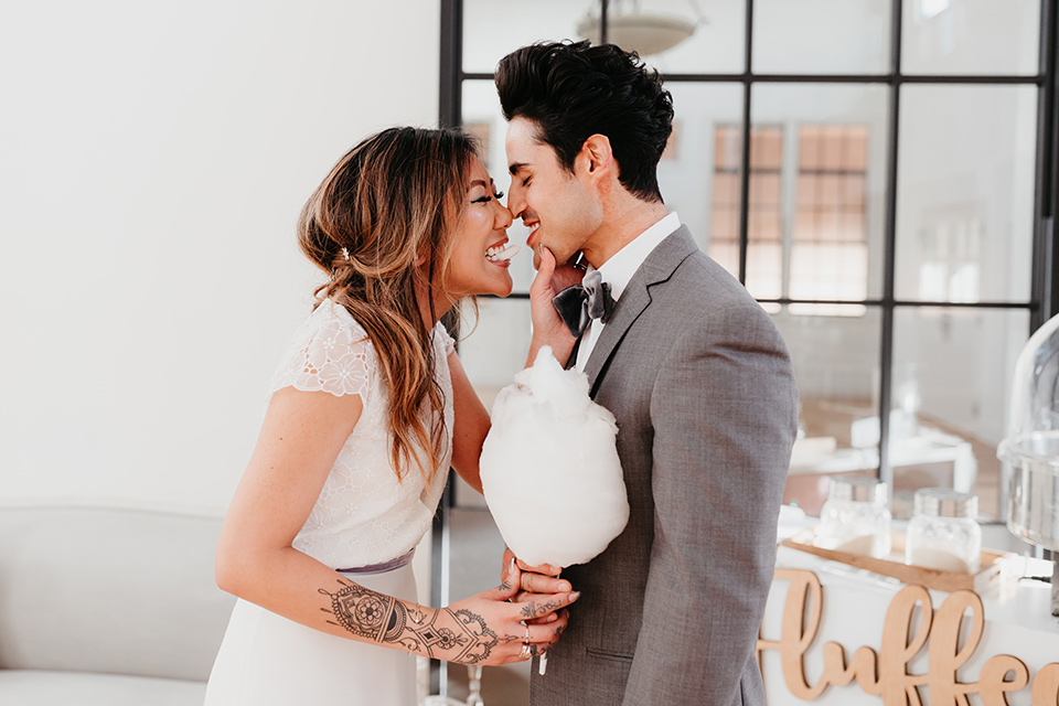 Building-177-Styled-Shoot-bride-and-groom-with-cotton-candy-bride-in-a-flowing-white-gown-with-short-sleeves-and-beading-detail-groom-in-a-grey-suit-with-a-grey-velvet-bow-tie