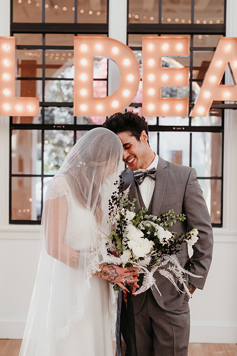 Building-177-Styled-Shoot-bride-with-veil-at-ceremony-with-groom-bride-in-a-flowing-white-gown-with-short-sleeves-and-beading-detail-groom-in-a-grey-suit-with-a-grey-velvet-bow-tie