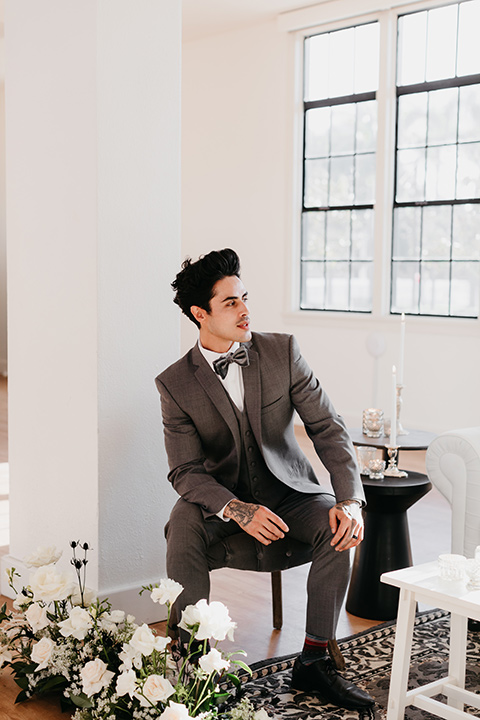 Building-177-Styled-Shoot-groom-by-window-in-a-grey-suit-with-a-grey-velvet-bow-tie