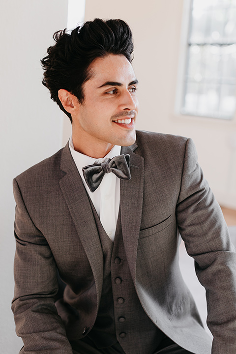 Building-177-Styled-Shoot-groom-looking-away-from-camera-in-a-grey-suit-with-a-grey-velvet-bow-tie