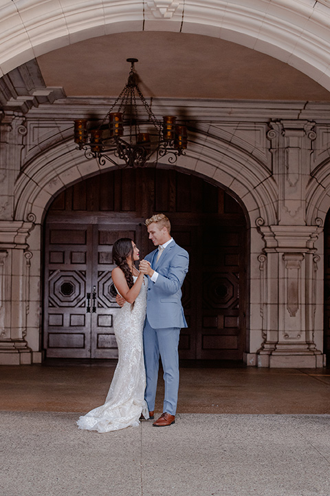  bride and groom dancing bride in a form fitting lace gown with thin straps groom in a light blue suit