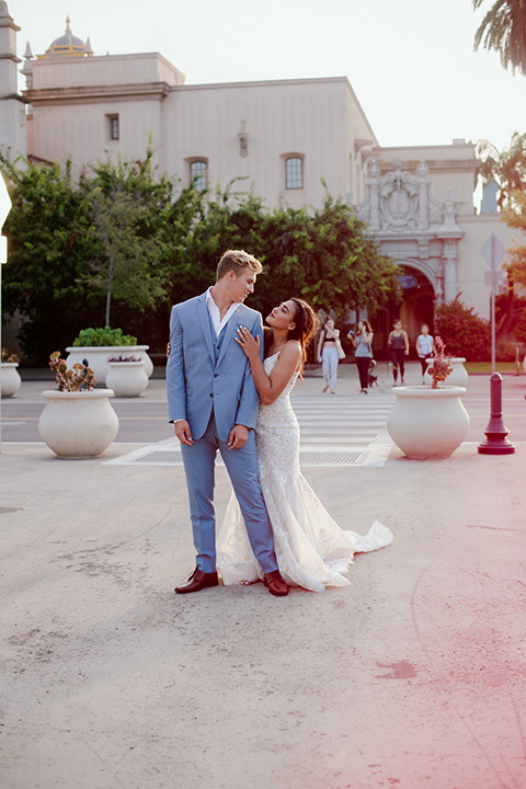 bride and groom in the square bride in a form fitting lace gown with thin straps groom in a light blue suit