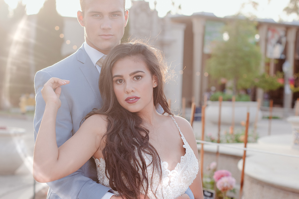 California Dreaming Shoot bride and groom looking at the camera bride in a lace form fitting gown with thin straps groom in a light blue suit