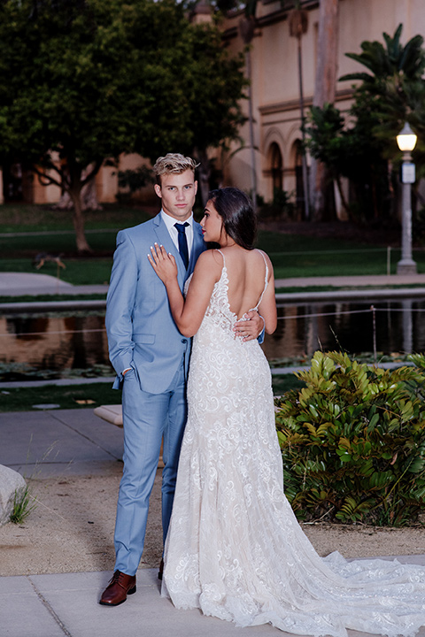 California Dreaming Shoot groom facing camera bride facing groom bride in a form fitting lace gown with thin straps groom in a light blue suit