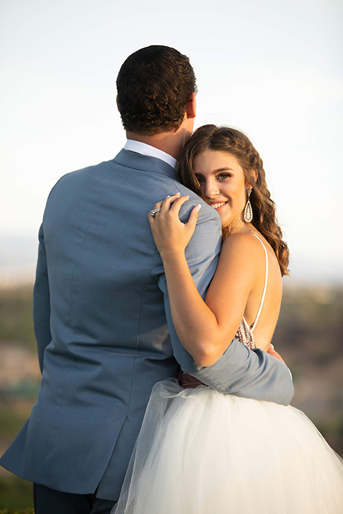 Callaway-Styled-Shoot-bride-looking-at-camera-groom-back-towards-camera-bride-in-a-tulle-ballgown-with-a-colorful-beaded-bodice-groom-in-a-light-blue-suit