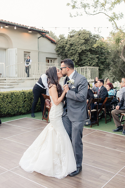 kellogg-house-pomona-wedding-bride-and-groom-dancing-bride-in-a-lace-mermaid-gown-with-a-high-neckline-and-the-groom-in-a-dark-grey-tuxedo-with-a-black-bow-tie