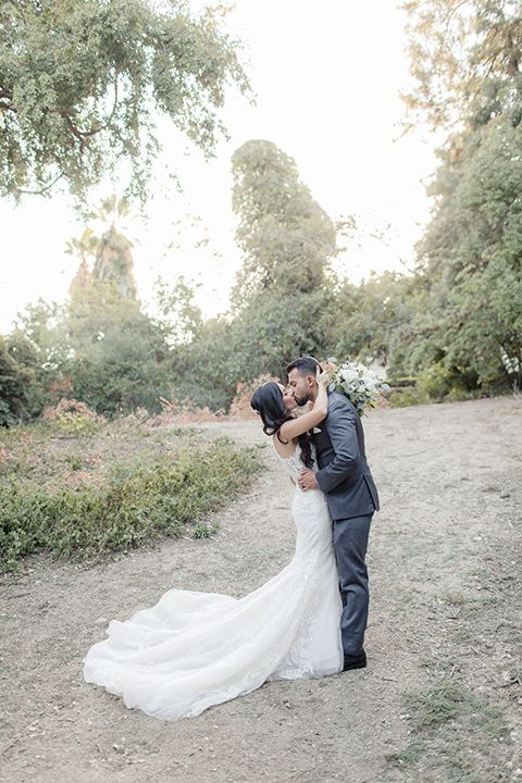 kellogg-house-pomona-wedding-bride-and-groom-kissing-bride-in-a-lace-mermaid-gown-with-a-high-neckline-and-the-groom-in-a-dark-grey-tuxedo-with-a-black-bow-tie