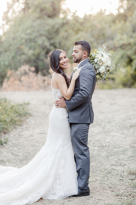 kellogg-house-pomona-wedding-bride-and-groom-looking-at-each-other-bride-in-a-lace-white-gown-with-a-high-neckline-and-a-mermaid-style-skirt-and-the-groom-in-a-dark-grey-tuxedo-with-a-black-bow-tie