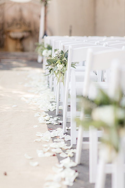 kellogg-house-pomona-wedding-ceremony-chairs-in-white-with-green-simple=florals-hanging-from-them