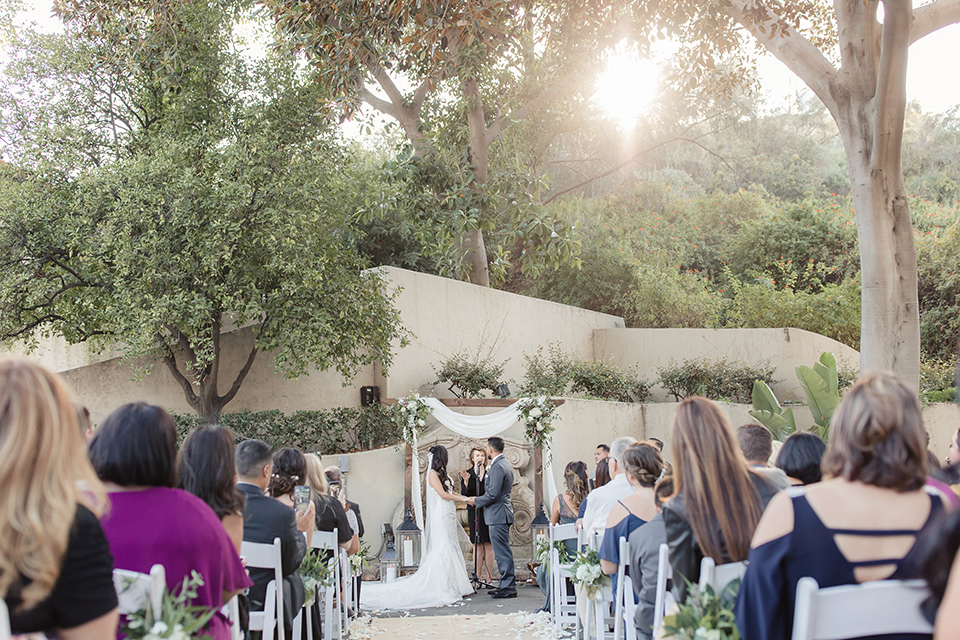 kellogg-house-pomona-wedding-ceremony-with-the-bride-in-a-whtie-lace-gown-and-the-groom-in-a-dark-grey-tuxedo