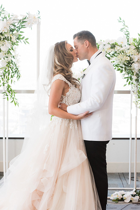 City-club-shoot-bride-and-goom-kiss-bride-in-a-white-ballgown-with-straps-and-a-sweetheart-neckling-groom-in-a-white-coat-with-black-pants