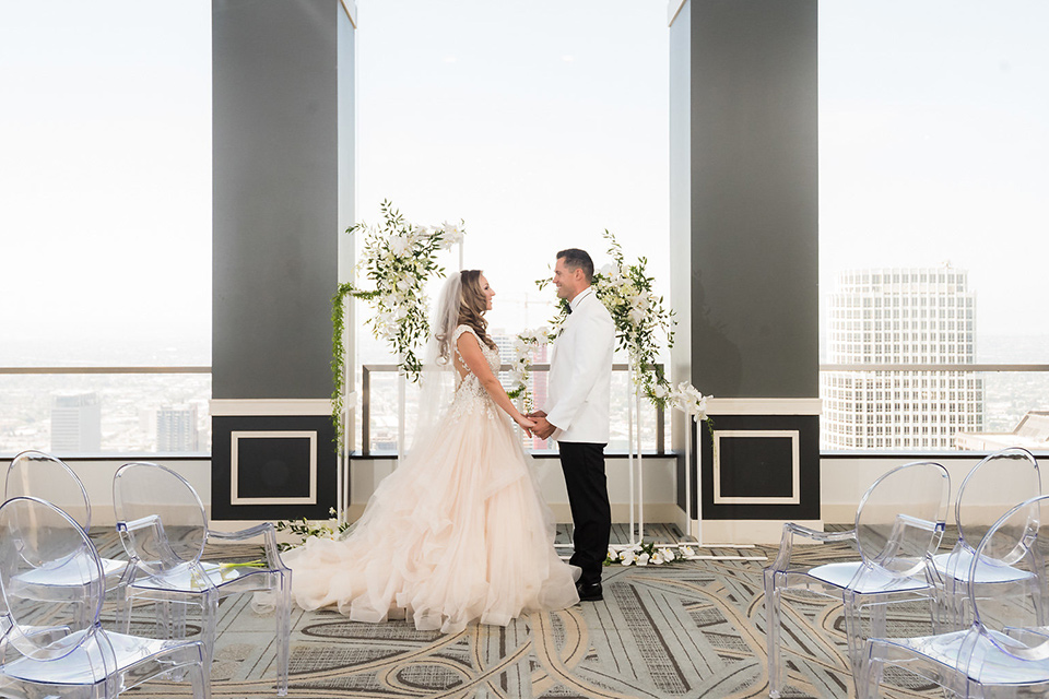 City-club-shoot-bride-and-groom-at-ceremony-bride-in-a-white-ballgown-with-a-sweetheart-neckline-and-straps-groom-in-a-white-coat-with-black-pants