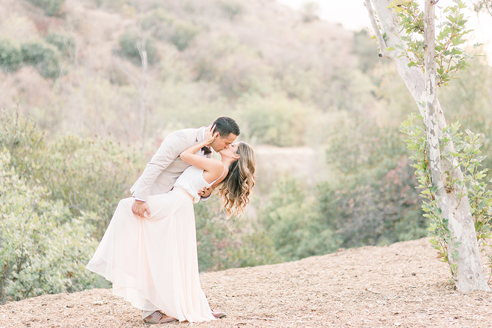 Claudia+Johns-meadow-elopement-groom-dipping-bride-bride-in-a-blush-skirt-and-white-silk-top-the-groom-is-in-a-tan-suit-with-a-brown-bow-tie