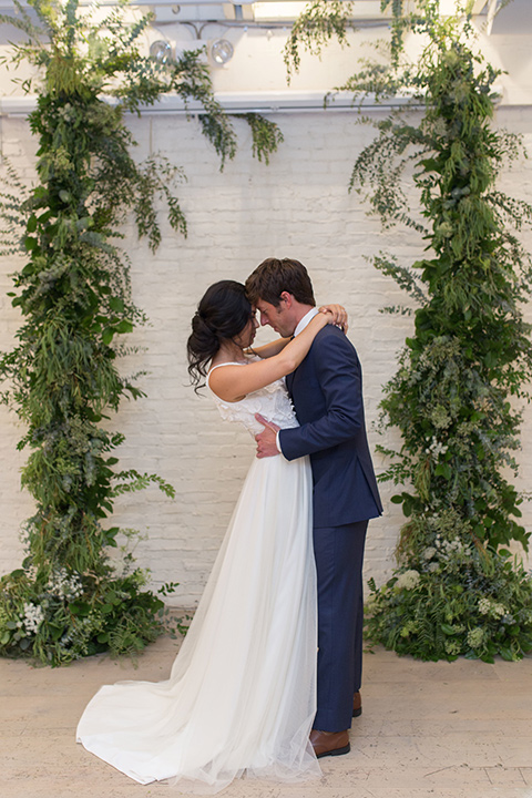 ”Cooks-Chapel-Shoot-bride-and-groom-facing-each-other-bride-in-a-soft-flowing-gown-with-a-plunging-neckline-while-the-groom-is-in-a-dark-blue-suit-with-a-navy-long-tie-and-brown-shoes"