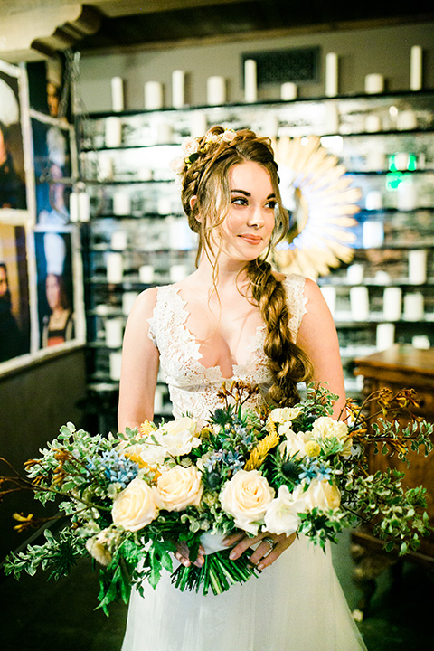 Wedding bride standing in a white lace ballgown with a bodice and straps while holding a bouquet of flowers