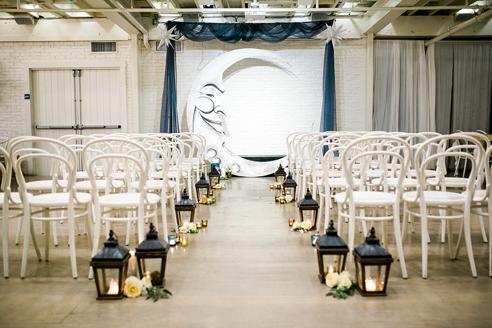  Cooks Chapel Wedding ceremony space with white iron metal chairs and a painted moon arch with black iron lanterns on the floor of the aisle. 