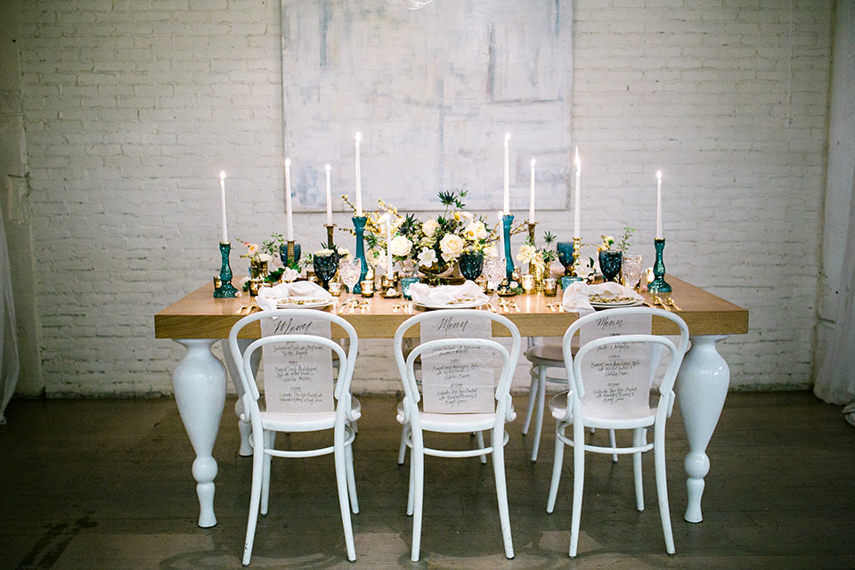 Cooks chapel wedding table set up with a wooden table, florals, candles and white chairs