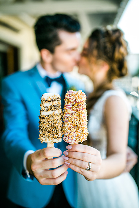 Bride and groom holding popsicles from the anaheim packing house with the bride in a white ballgown and the groom in a light blue suit