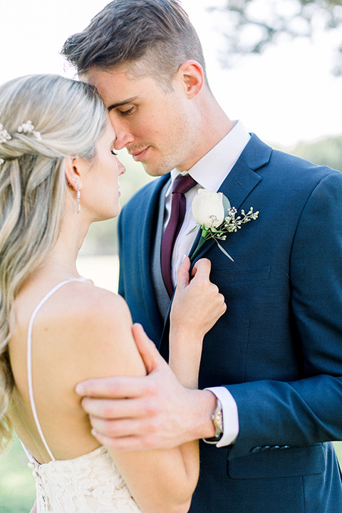 red-barn-wedding-bride-and-groom-heads-touching-close-bride-in-a-lace-fitted-dress-with-thin-straps-groom-in-a-blue-suit-with-grey-vest-and-burgundy-tie