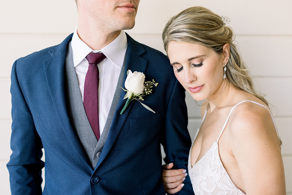 red-barn-wedding-close-up-on-bride-and-groom-grooms-face-cut-out-of-frame-bride-in-a-lace-fitted-dress-with-thin-straps-groom-in-a-blue-suit-with-grey-vest-and-burgundy-tie