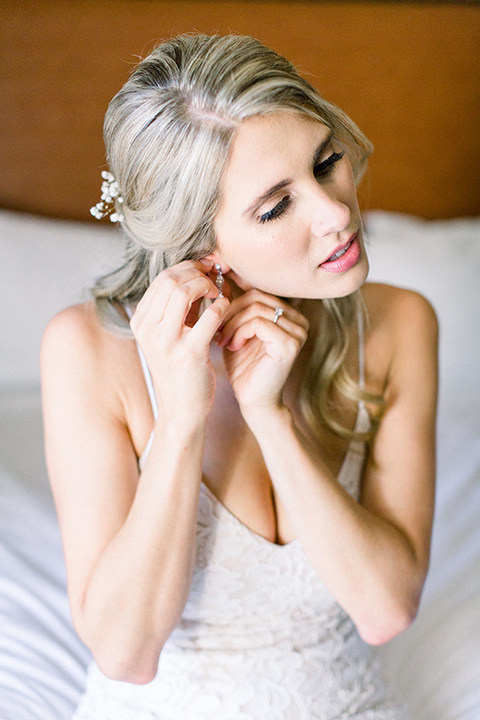 red-barn-wedding-bride-putting-earrings-bride-in-a-lace-fitted-dress-with-thin-straps-groom-in-a-blue-suit-with-grey-vest-and-burgundy-tie