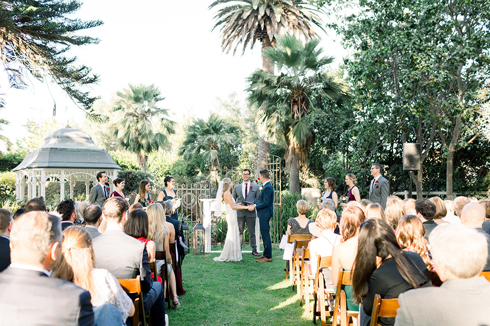 red-barn-wedding-ceremony-bride-and-groom-walking-down-after-ceremont-bride-in-a-lace-fitted-dress-with-thin-straps-groom-in-a-blue-suit-with-grey-vest-and-burgundy-tie