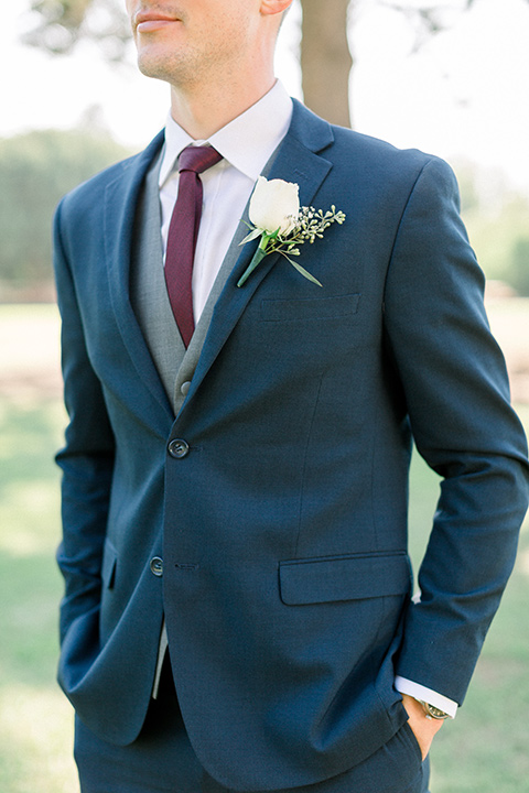 red-barn-wedding-close-up-on-groom-groom-in-a-blue-suit-with-grey-vest-and-burgundy-tie