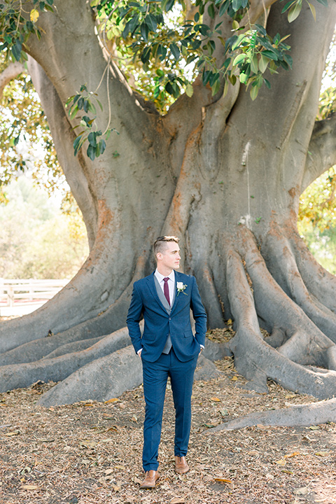 red-barn-wedding-groom-by-tree-groom-in-a-blue-suit-with-grey-vest-and-burgundy-tie