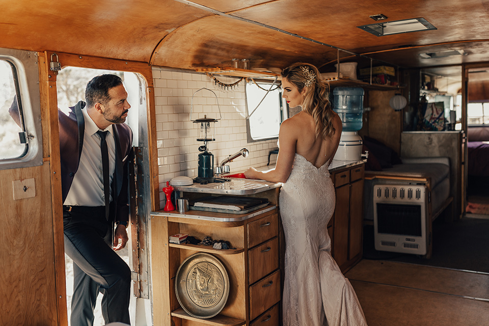 Bohemian-Desert-Shoot-bride-and-groom-in-rv-bride-in-a-formfitting-gown-with-lace-detailing-and-a-sweetheart-neckline-groom-in-a-burgundy-shawl-lapel-tuxedo-with-a-black-long-tie