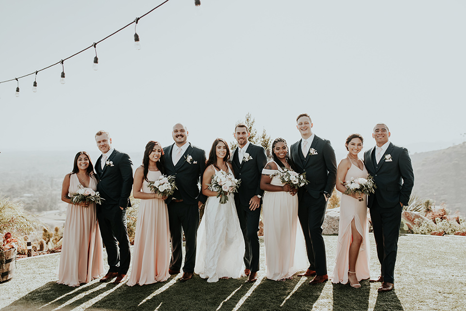 Dragon-point-villa-wedding-bridal-party-bridesmaids-in-light-pink-dresses-groomsmen-in-black-suits-with-light-pink-accessories-bride-in-a-white-ballgown-with-pockets-and-thin-straps-groom-in-a-black-suit-with-a-white-tie
