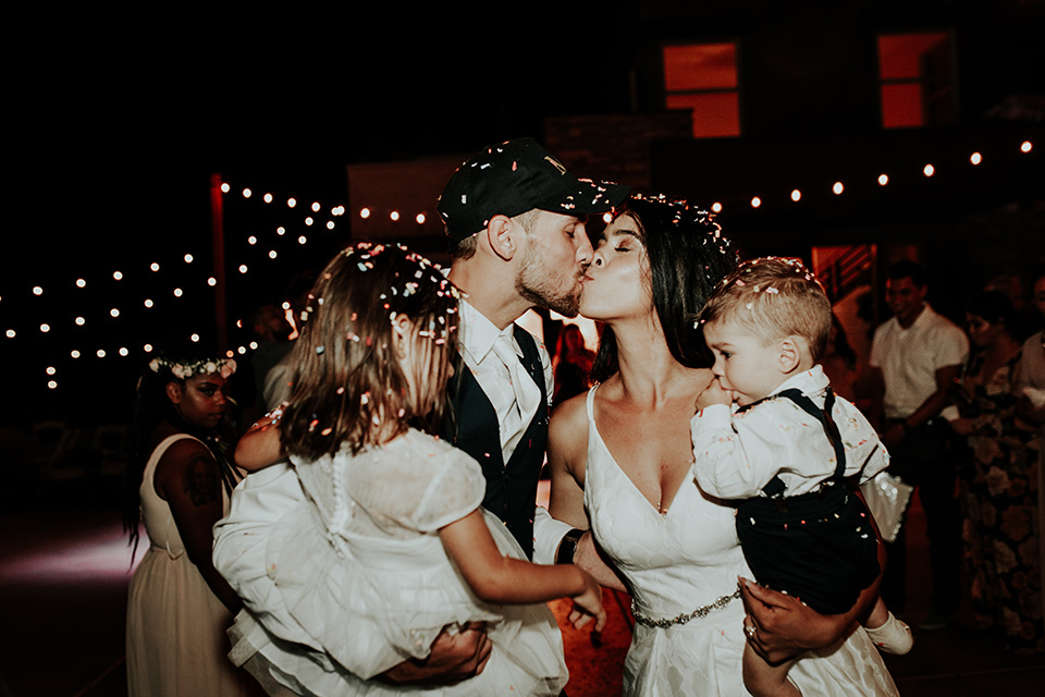 Dragon-point-villa-wedding-bride-and-groom-kissing-with-confetti-bride-in-a-white-ballgown-with-pockets-and-thin-straps-groom-in-a-black-suit-with-a-white-tie